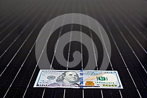 American money on solar panel surface. Renewable energy cost