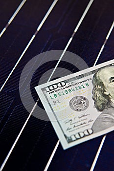 American money on solar panel surface. Renewable energy cost