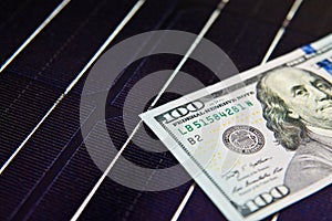 American money on solar panel surface. Renewable energy cost