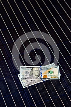 American money on solar panel surface. Renewable energy cost