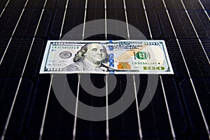 American money on solar panel surface. Renewable energy cost photo