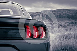 American muscle car stylized in black and white with red accent tail light