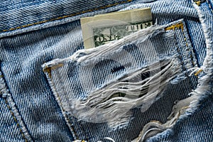 American one dollars in a ripped old jeans pocket, closeup. The concept of crisis, poverty