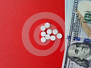 American one hundred dollar bills and pills on red background