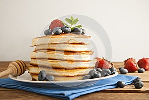 American pancakes or fritters served with strawberry and blueberry jam, delicious dessert for breakfast, rustic style, wooden back