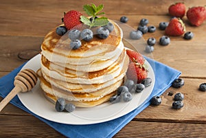 American pancakes or fritters served with strawberry and blueberry jam, delicious dessert for breakfast, rustic style, wooden back