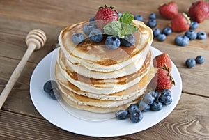 American pancakes or fritters served with strawberry and blueberry jam, delicious dessert for breakfast, rustic style, wooden back