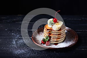 American pancakes on a plate with banana, cherry and mint