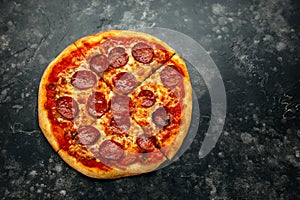 American pepperoni cheese pizza on rustic black background