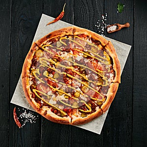 American pizza with minced meat on dark wood background. Italian dish - homemade pizza with bolognese sauce, pickled and tomatoes