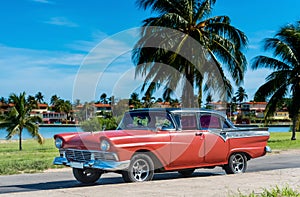 American red Ford classic car with black roof parked under blue sky near the beach in Havana Cuba - Serie Cuba Reportage