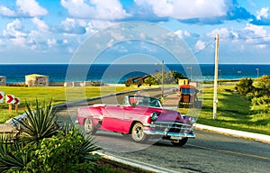 American red pink 1954 convertible vintage car on the fortress el Morro near the beach in Havana Cuba - Serie Cuba Reportage