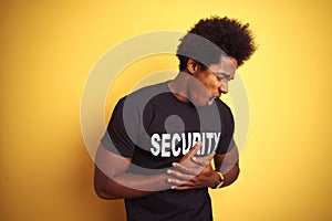 American safeguard man with afro hair wearing security uniform over isolated yellow background with hand on stomach because