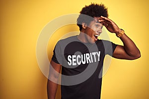 American safeguard man with afro hair wearing security uniform over isolated yellow background very happy and smiling looking far