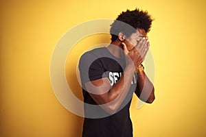 American safeguard man with afro hair wearing security uniform over  yellow background with sad expression covering face