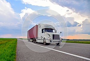 American semi truck transporting sea container on highway on sunset background. Shipping Containers Delivery, Maritime Services