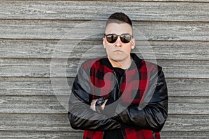 American serious young hipster man in black sunglasses in a vintage red checkered jacket in a black t-shirt