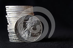 An American Silver Eagle coin, against a stack of silver eagle coins