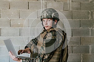 American soldier in military uniform using laptop computer for drone controlling and to stay in contact with friends and