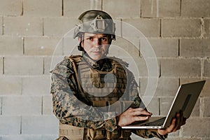 American soldier in military uniform using laptop computer for drone controlling and to stay in contact with friends and