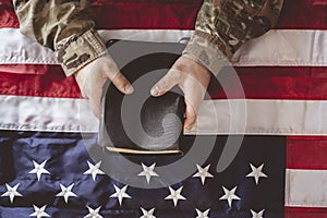 American soldier mourning and praying with the Bible in his hands and the American flag