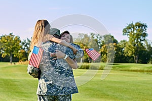 American soldier reunited with his family in park.