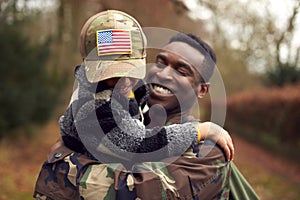 American Soldier In Uniform Returning Home To Family On Leave With Son Wearing Army Cap