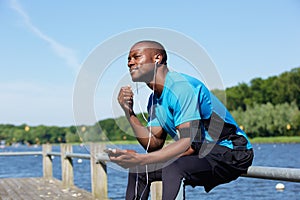 American sports man sitting outside listening to music