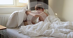 American teen boy is waking up in the morning at new year eve, looking for gift, present