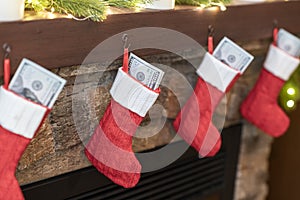 American, US dollars in Ñhristmas red socks for gifts on the fireplace in bokeh lights.