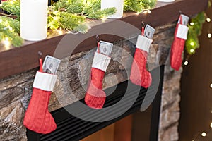 American, US dollars in Ñhristmas red socks for gifts on the fireplace in bokeh lights.