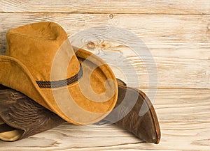 American West cowboy boots and hat on wood texture background