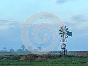 American windmill in foggy farmland at sunrise