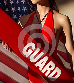 American woman lifeguard with rescue tube and whistle equipment against USA flag