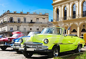 American yellow 1951 Chevrolet and a red 1957 convertible vintage car parked in the historical