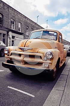 American yellow oldtimer from 50s or 60s parked in a London street, UK