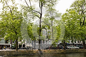 Amesterdam, Holland Ã¢â¬â 2019. Cars and bicycles parked near canal of river Amstel in narrow streets of Amsterdam city. Old dutch