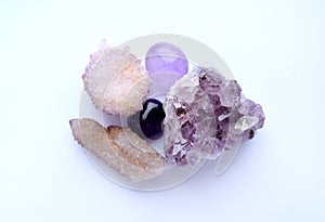 Amethyst purple natural stones in different varieties. Tumbled stones, amethyst druse and cactus quartz crystals. Cactus quartz,