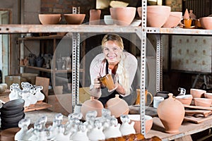 Amiable female artisan having ceramics in workshop