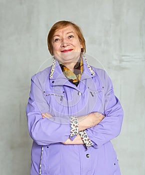 Amiable senior woman in light purple jacket with crossed arms