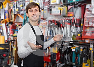 Amiable young salesman in apron with tools