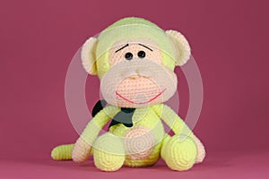 Soft DIY toy made of natural cotton and wool. Cute little monkey with bow on neck crocheted, handmade art. Amigurumi one