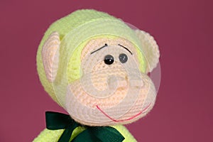 Soft DIY toy made of natural cotton and wool. Cute little monkey with bow on neck crocheted, handmade art. Amigurumi one