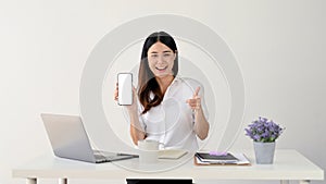 Amiling Asian businesswoman showing her smartphone with white mockup screen