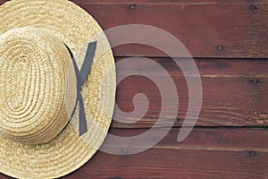 Amish man's straw hat hangs on a red barn door