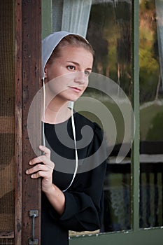 Amish Woman Looks out Screen Door