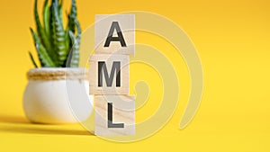 AML - ANTI-MONEY LAUNDERING - concept with wooden blocks on table, yellow background