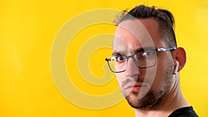 Suspicious man with glasses and headphones looks to the left side of the screen.