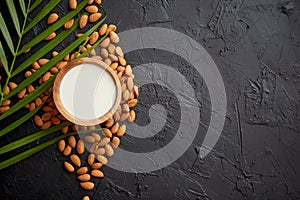 Amond seeds with bowl of fresh natural milk placed on black stone background