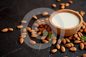 Amond seeds with bowl of fresh natural milk placed on black stone background